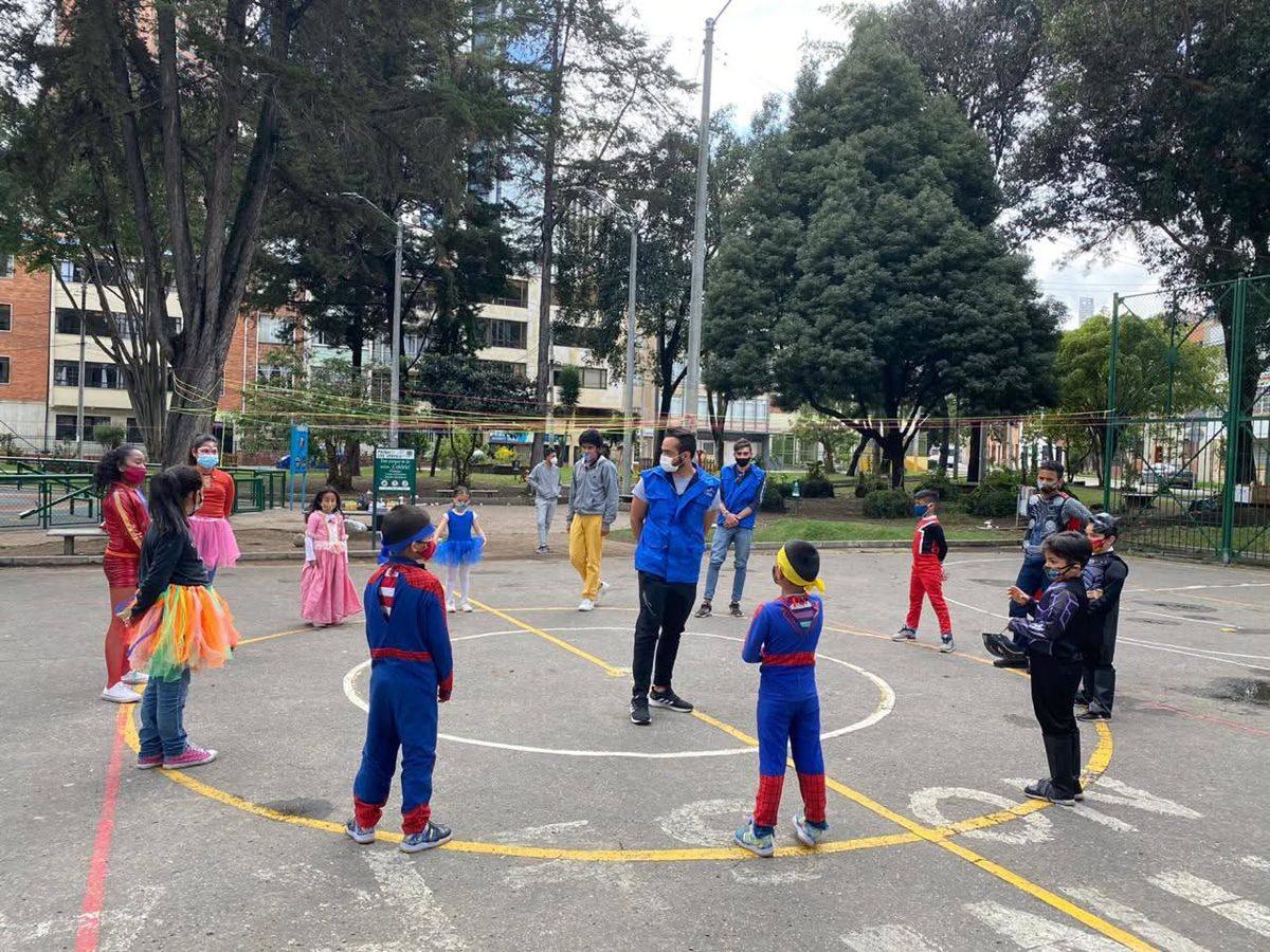 Niñas y niños juegan en ronda en una cancha de Bogotá durante una jornada comunitaria de REDH