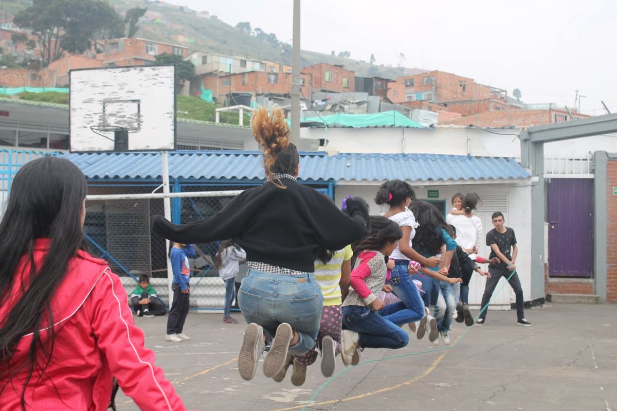 Niñas y niños saltan la cuerda en el patio de un barrio de Bogotá